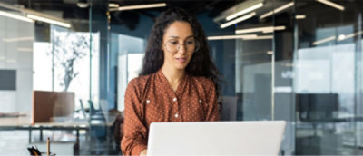 A person in a red shirt and glasses looking at a computer