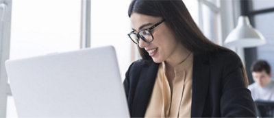 "A person in glasses looking at a computer