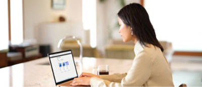 Žena sjedi za stolom i koristi prijenosno računalo.