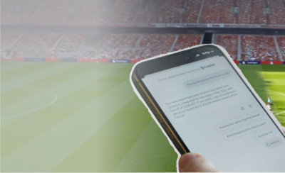 Phone showing Copilot football match preview in front of a stadium.