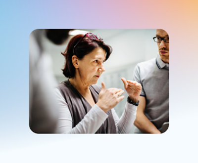 Uma mulher de óculos gesticula enquanto fala com um homem, que está ouvindo atentamente