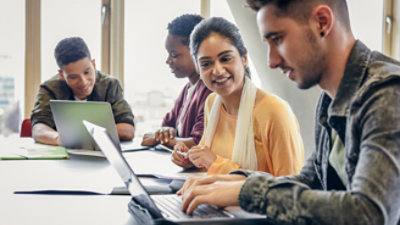 En gruppe personer, der kigger på en bærbar computer.