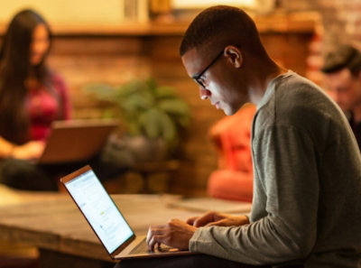 A man in a grey shirt using a laptop.