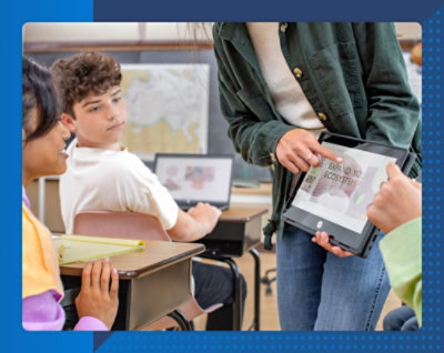 A person holding a tablet with a group of students in the background
