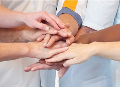 Группа людей соединяет руки.