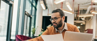 A man with a beard and glasses looking at a piece of paper.
