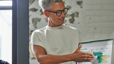 A woman wearing glasses holding a laptop.