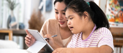 Adult guiding a child using a tablet for learning at home.