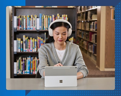 Person wearing headphones using a tablet in a library with bookshelves in the background.