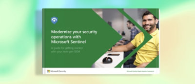 A man in a yellow shirt stands in front of a green and white advertisement for Microsoft Sentinel.