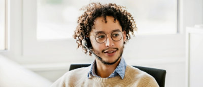 A man with curly hair wearing a headset.