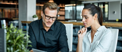 A man and woman looking at a laptop.