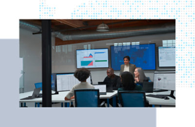 Team collaborating around desks with large data dashboards displayed.