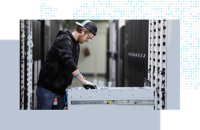 Technician installing server hardware in a data center aisle.