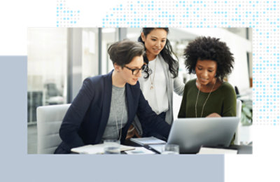 Three coworkers gathered around a laptop, reviewing information during a discussion.