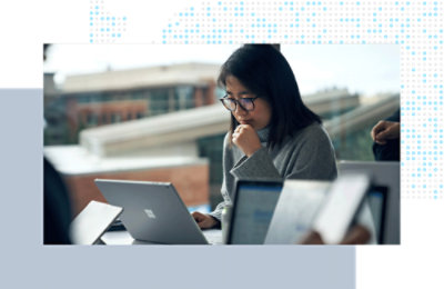 Person seated at a table, focused on working on a laptop in a shared workspace.