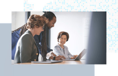 Three coworkers gathered around a laptop, reviewing and discussing information together.