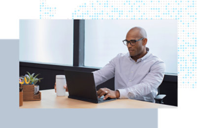 Person seated at a desk, working on a laptop in a modern office setting.