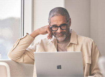 Улыбающийся человек смотрит на ноутбук.