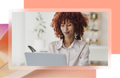 A woman with curly red hair looking at a laptop.