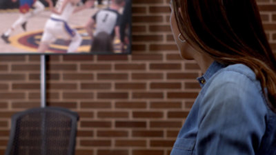 Eine Frau in einem blauen Hemd schaut fern.