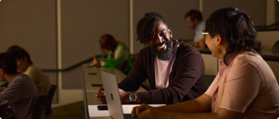 People working together at desks using laptops in an indoor workspace.