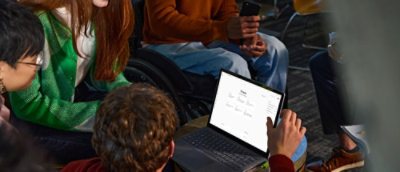 A group viewing content together on a laptop and tablet while seated.