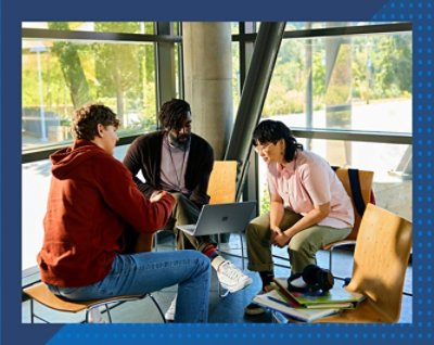 Three people seated in a modern space reviewing content together on a laptop.