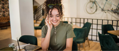 A person with curly hair and green shirt talking on a cell phone