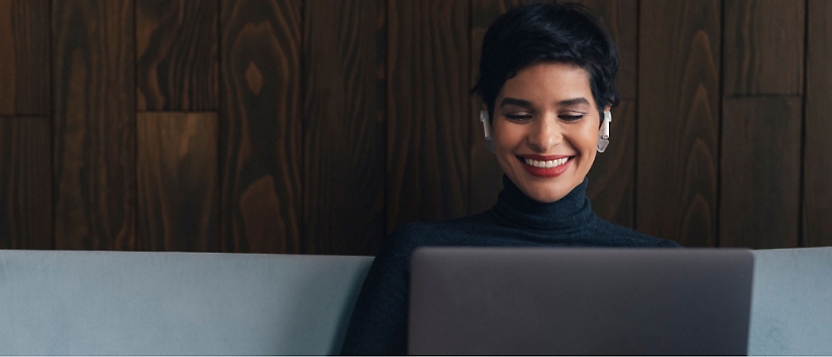 A woman smiling at a laptop.