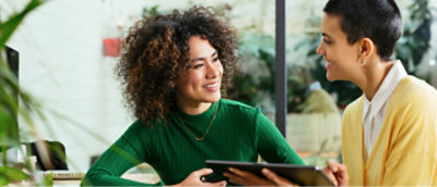 A woman in a green shirt with short curly hair, smiling and holding a phone