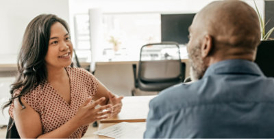 A woman in a pink shirt and a man in a blue shirt talking.