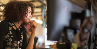 A woman with curly hair looking at a computer screen.