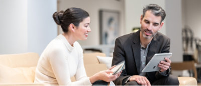 A man and woman sitting on a couch, with the man holding a tablet.