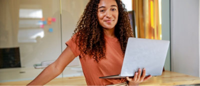 A woman with curly hair holding a laptop.