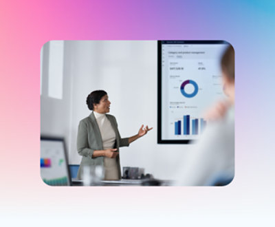 A person in professional attire is giving a presentation with charts and graphs displayed on a screen