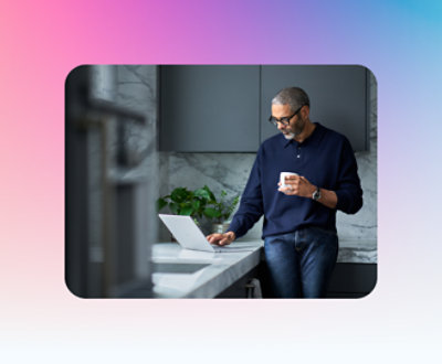 A person holding a cup and looking at a computer