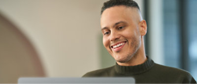 A close-up of a man's face smiling with a shaved head.