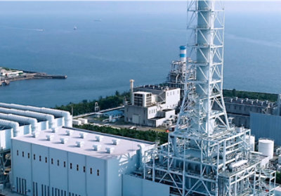 A large white factory with a large body of water.