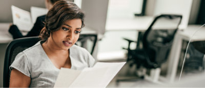 A woman sitting in a chair reading a paper.