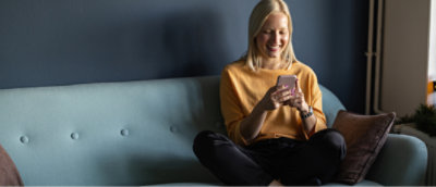 Uma mulher sentada em um sofá olhando para o telefone.