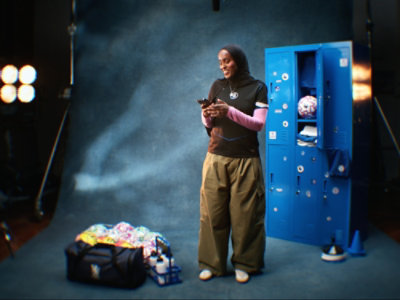 Person in sportswear standing by lockers while using a smartphone in a studio setting.