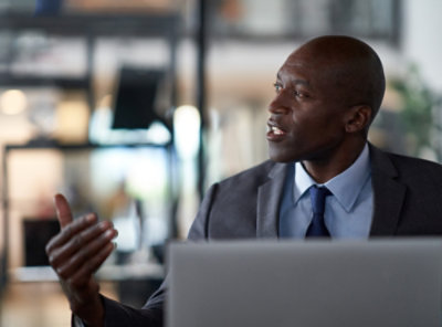 Seorang pria mengenakan jas berbicara dengan pria lain.