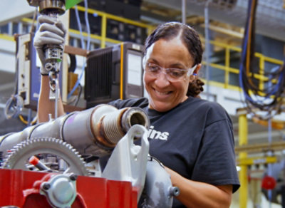A woman working on a machine with ins text visible.