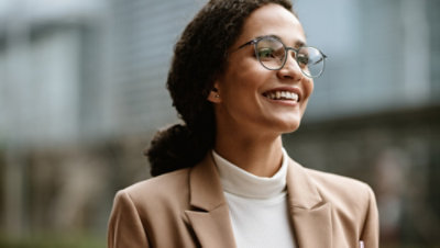 Seorang perempuan mengenakan kacamata dan jas.