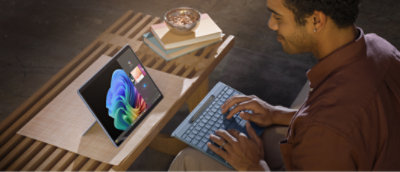 A man wearing a brown shirt using a laptop with a colorful logo on the screen.