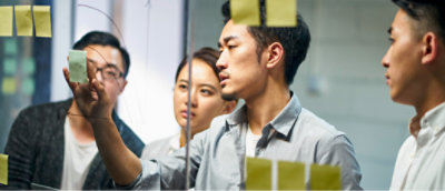 A man and woman writing on a glass wall.