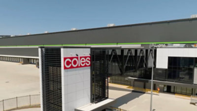 A building with a white and red Coles sign on a white wall.