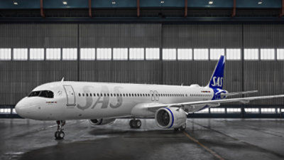 A large white airplane in a hangar with SAS written on it.