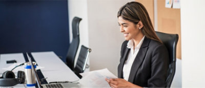 A woman in a suit smiling at a computer.